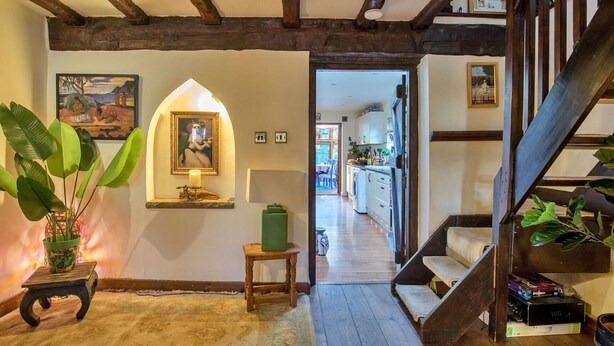 A hallway with wooden beams, a staircase, a small table with a plant, and a view into a kitchen area. - Stunning  villa for 4 people with WIFI and pets allowed (Felbridge)