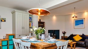 A dining area with a wooden table set for four, surrounded by white chairs.