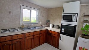 A kitchen with a gas stove, sink, microwave, oven, and a refrigerator. - Apartment T3 with swimming pool and garden for your vacations in Guadeloupe (Baie-Mahault)