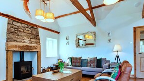 A cozy living room with a stone fireplace, wooden beams, a sofa set, and a coffee table. - Beautiful  villa for 4 guests with WIFI and terrace (Edlingham)