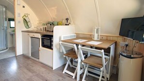 Cocina compacta con una mesa de madera, dos sillas, un tostador y un lavamanos.