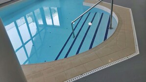 An indoor swimming pool with clear lane markings, a metal handrail, and a tiled floor. - Lovely apartment for 5 guests with pool, WIFI, TV and balcony (Tenby)