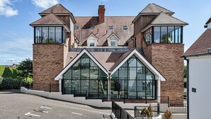 A modern building with large windows and a brick facade. - Lovely apartment for 5 guests with pool, WIFI, TV and balcony (Tenby)