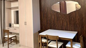 Un comedor moderno con una mesa y sillas de madera, una lámpara colgante y un armario con espejo.