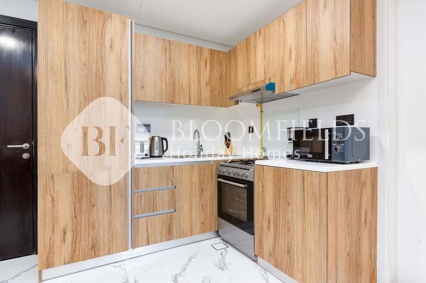 A modern kitchen with wooden cabinetry, a built-in oven, a microwave, and a coffee maker.