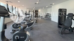 A gym with various exercise equipment including treadmills, a weight machine, and a bench. - Bloomfields Skyline 1Br In Al Maryah  (Abu Dhabi)