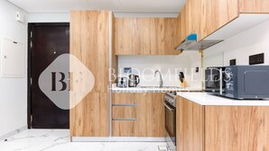 A modern kitchen with wooden cabinets, a microwave, and a stove. - Bloomfields Skyline 1Br In Al Maryah  (Abu Dhabi)