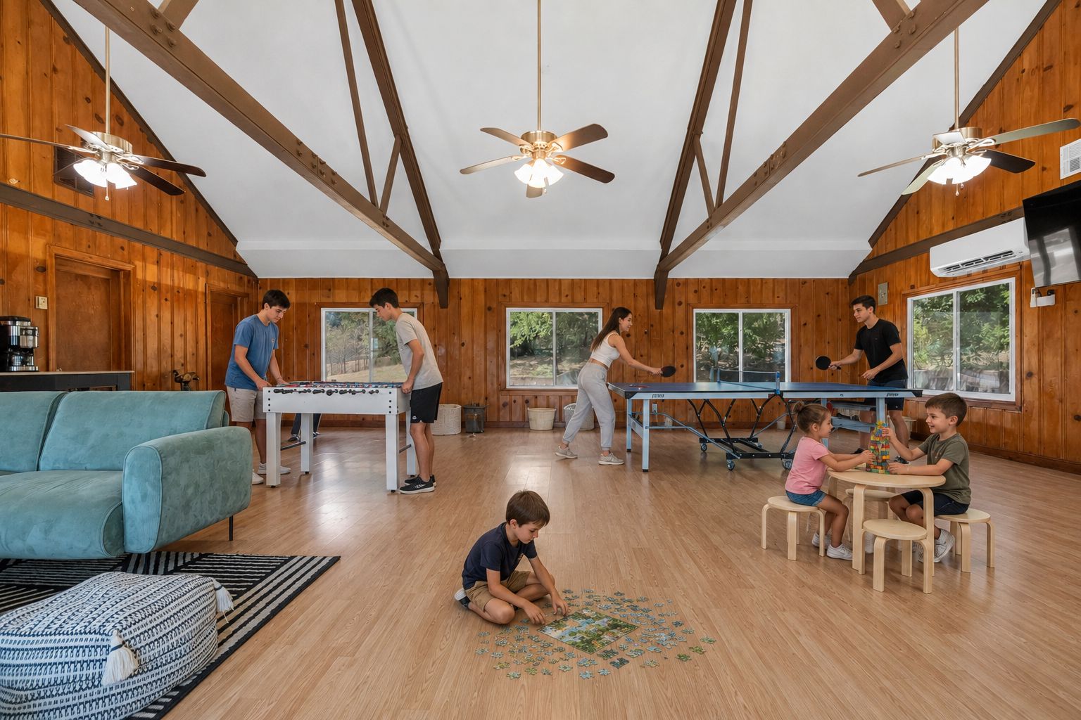 A room with wooden walls, ceiling fans, a foosball table, a ping pong table, and a foosball table.