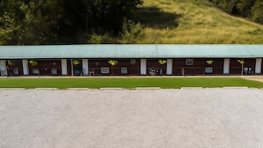 A building with a green roof, multiple windows, and a gravel driveway. - Cozy & Spacious Wooden Suite By The Lake | Texoma Shores Resort (Madill)