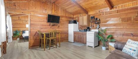 L'intérieur d'un chalet en bois comprend un coin repas, une cuisine et un canapé.