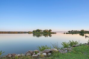 A calm lake with a dock, surrounded by rocks and greenery.