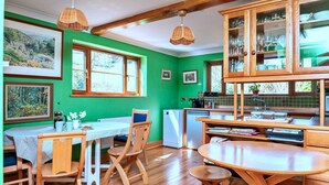 A kitchen with wooden cabinets, a dining table, chairs, and a refrigerator.