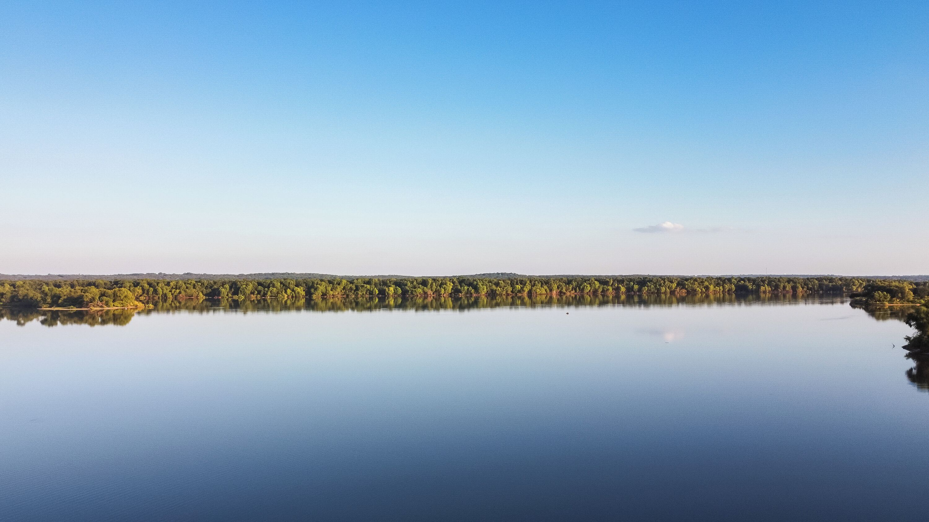 Un lac paisible, bordé d’une forêt et surplombé d’un ciel dégagé.
