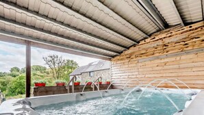 Un bain à remous avec des parois en bois et une vue sur la verdure.
