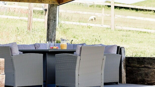 An outdoor patio with wicker furniture and a pool area.