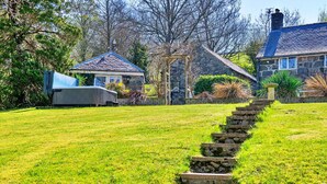A stone staircase leading up to a house with a stone facade and a blue roof.