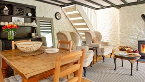 Un salón acogedor con una mesa de comedor de madera, sillas cómodas, una chimenea y una escalera que sube a otro nivel.