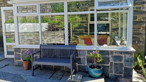 A conservatory with a bench and potted plants.