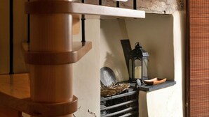 Una escalera de caracol de madera con un interior rústico, una pared de piedra y un farol en un estante.