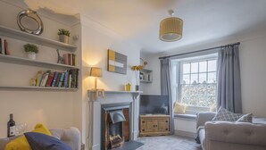 Una sala de estar acogedora con chimenea, sofá, estantería y ventana con cortinas.