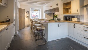 Una cocina moderna con armarios blancos, una isla central con taburetes, horno empotrado y un amplio ventanal que proporciona luz natural.