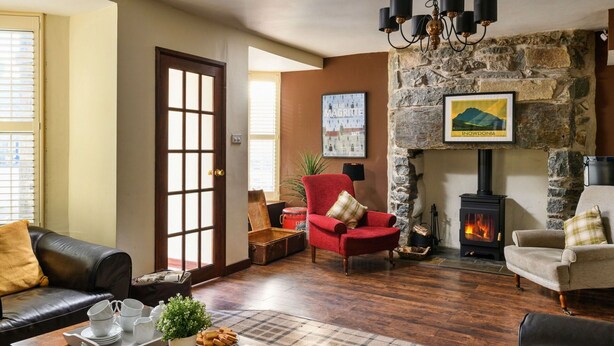 A cozy living room with a stone fireplace, leather sofas, and a wooden coffee table. - Stunning  villa for 10 people with WIFI and pets allowed (Portmadoc)