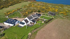 A coastal property with multiple buildings, including a main house with a large patio and a smaller structure. - Stunning  villa for 8 guests with WIFI, TV and balcony (Aberdaron)