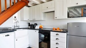 Una cocina con armarios blancos, lavavajillas Bosch, estufa y refrigerador FridgeMaster.