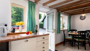 Une cuisine avec un plafond en bois, un coin repas avec une table et des chaises, et une fenêtre avec des rideaux.