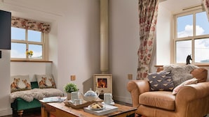Una sala de estar acogedora con chimenea, un sofá, una mesa de centro y una ventana con vistas.