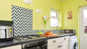 A kitchen with a gas stove, oven, and a washing machine. - Beautiful  villa for 4 guests with WIFI and pets allowed (Foryd)