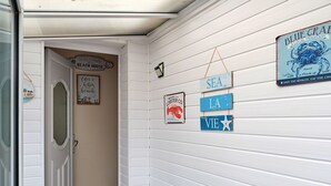 A hallway with a door leading to a room, decorated with nautical-themed signs and a lobster sign. - Beautiful  villa for 4 guests with WIFI and pets allowed (Foryd)