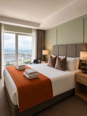 A hotel room with a large bed, two bedside lamps, a view of the city, and a balcony. - Bayview Lodge (Downings)