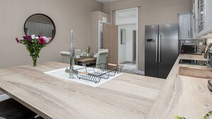 Una cuina moderna amb un frigorífic integrat, una zona de dinar amb taula i cadires, i un vas de flors al taulell.