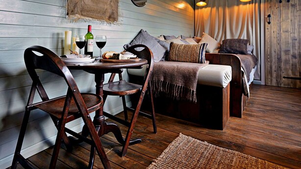 Una habitación acogedora con una mesa de comedor de madera, dos sillas, un sofá y una cama.