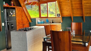 Une cuisine dotée d’un îlot central, de poutres en bois au plafond et offrant une vue sur l’extérieur.