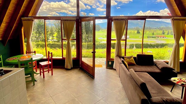 Il s’agit d’une pièce spacieuse dotée d’une grande fenêtre donnant sur un paysage verdoyant. On y trouve un canapé, une table à manger avec des chaises et un coin cuisine.
