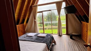 Une chambre avec un grand lit, un plancher en bois et une fenêtre avec des rideaux.