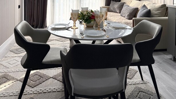 A modern dining area with a round table set for four, surrounded by dark chairs.