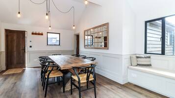 A dining area with a wooden table and chairs, a bench with cushions, and a large window.