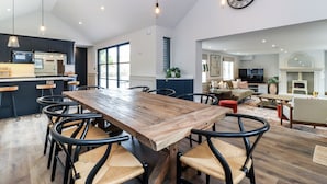 A spacious kitchen with a large wooden table and chairs, a dining area, and a living room with a sofa and TV. - Tuffs Farm (Kings Langley)