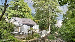 A stone bridge over a stream, surrounded by lush greenery and a white house with a garden. - Stunning  villa for 5 guests with WIFI and pets allowed (Llangelynin)