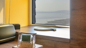 A kitchen with a wooden countertop, a sink, and a window overlooking a body of water.