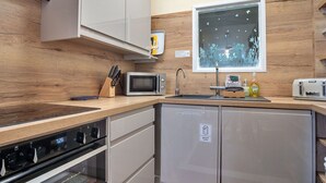 Eine kompakte Küche mit Mikrowelle, Toaster, Spüle und Geschirrspüler.