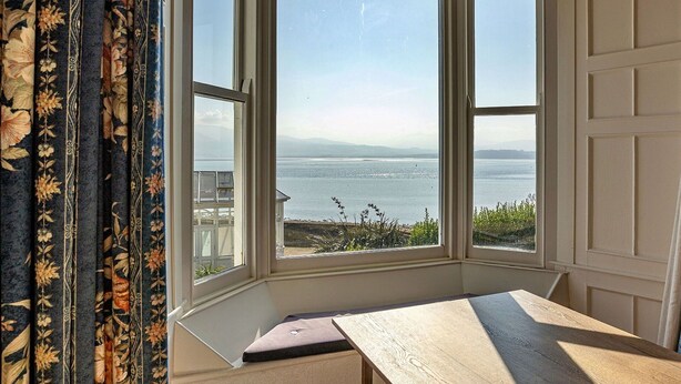 A bay window with a view of the sea and distant mountains.
