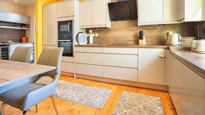 A modern kitchen with white cabinets, a wooden countertop, and a built-in oven.