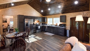 Una cocina amplia con electrodomésticos modernos, piso de madera y una zona de estar acogedora con chimenea.