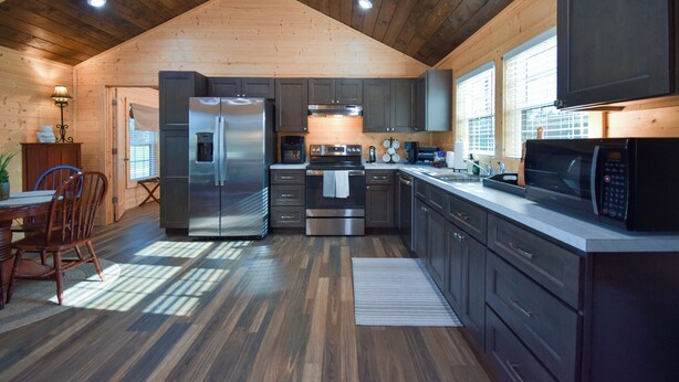 Una cocina moderna con vigas de madera en el techo, electrodomésticos de acero inoxidable y un amplio ventanal que proporciona luz natural.