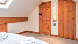 Un dormitorio con tragaluz, armario de madera y una cama con toallas dobladas.