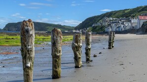 A beach with wooden posts and a coastal town in the background. - Stunning  villa for 4 people with WIFI, TV and pets allowed (Fraserburgh)